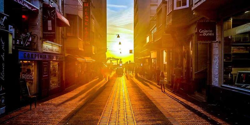 一位游客在社区公园拍照留念，背景是充满活力的社区街道，阳光洒在行人身上，显得温馨而生动。